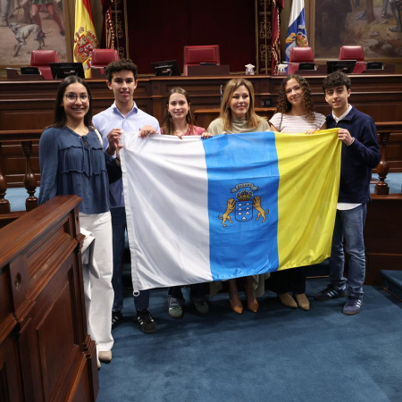 La presidenta del Parlamento entrega la bandera canaria que acompañará a los estudiantes seleccionados para la Ruta Quetzal 2026